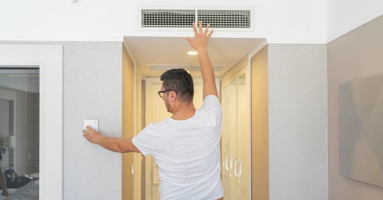 Man Adjusting The Room Temperature From The Air Conditioning Panel