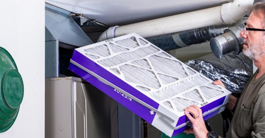 Home owner inserts a new clean filter into furnac