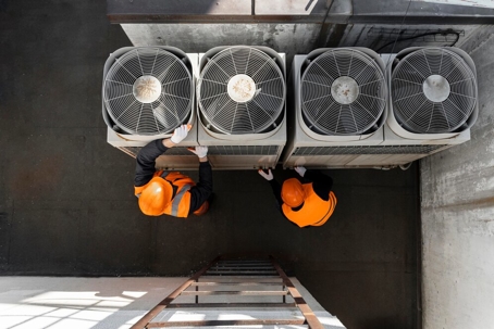 Overhead view of two technicians servicing industrial air conditioning units.