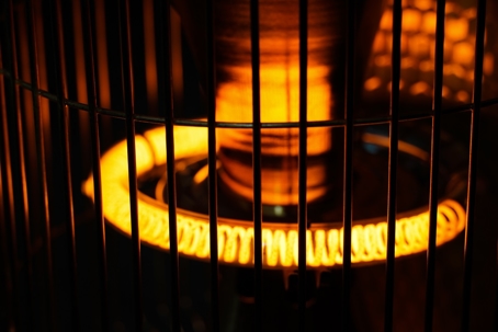 Close-up of a space heater showing the bright orange heating element behind safety bars.