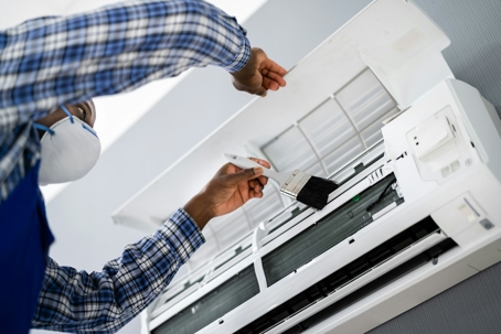 A technician cleaning an AC unit
