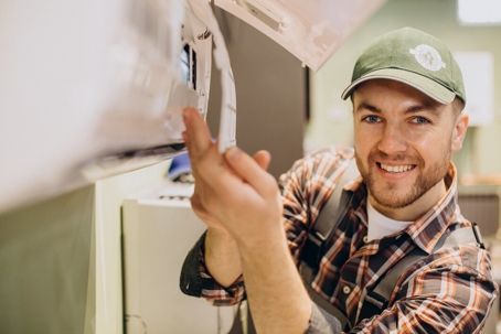 Smiling technician repairs an air conditioning unit.